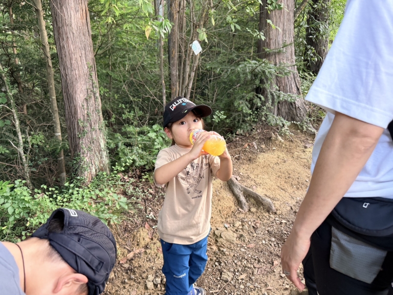 八重山の登りで木陰に立ち止まり水分補給する子ども