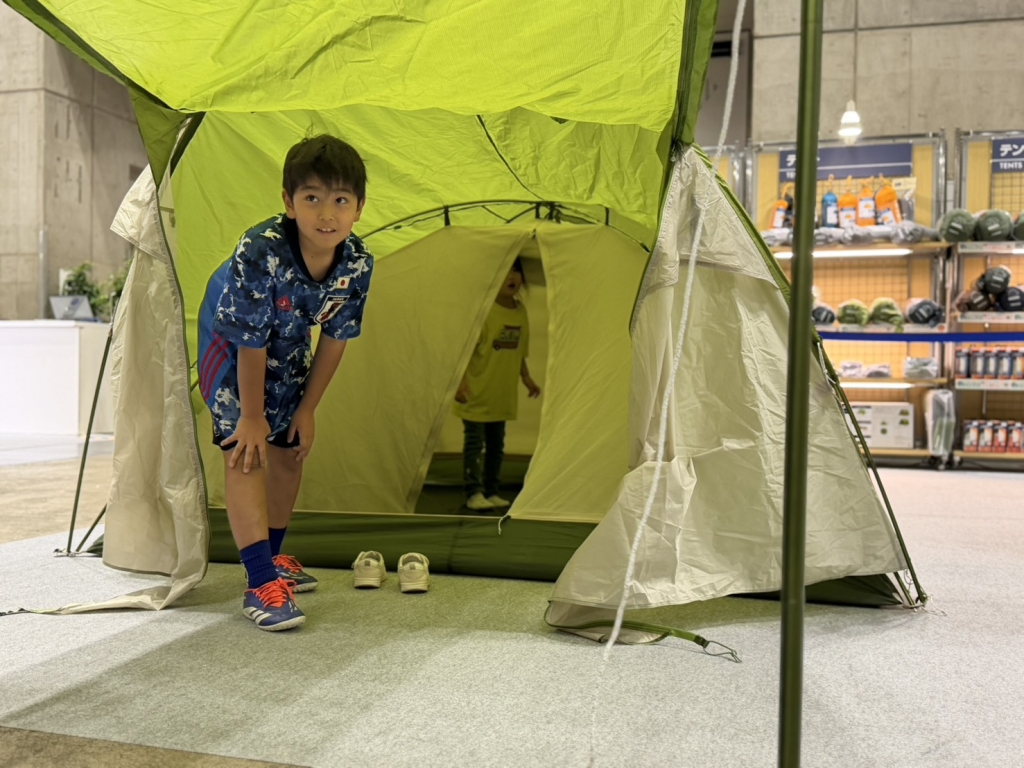 設営体験で完成したモンベルのテントに入る息子と娘
